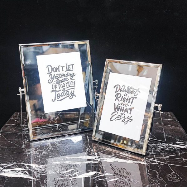 دو قاب عکس شیشه‌ای و فلزی نقره‌ای با پایه، مناسب دکوراسیون لوکس.