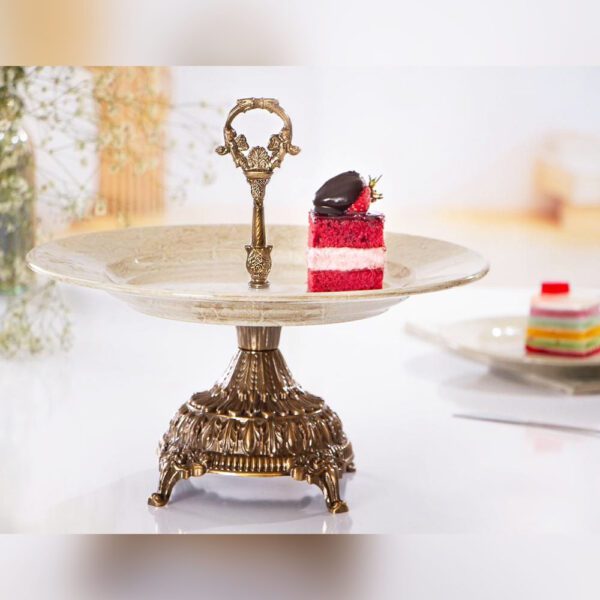 شیرینی خوری پایه دار آنتیک مدل ماربل با دسته فلزی و یک تکه کیک روی سینی