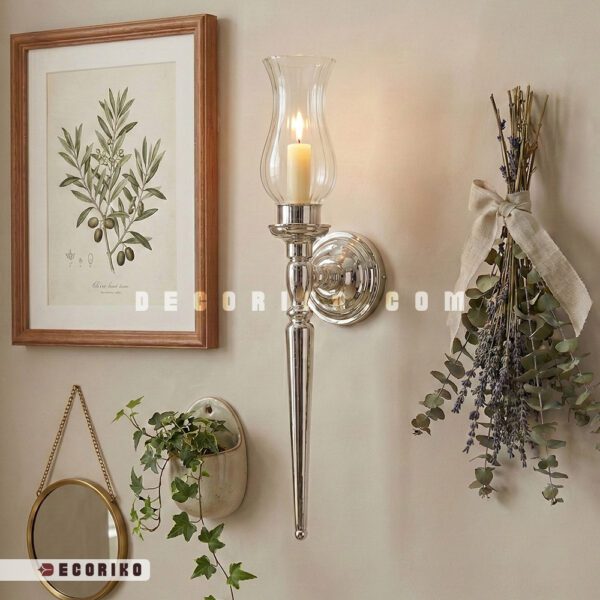 شمعدان دیواری فلزی رنگ نقره‌ای با حباب شیشه‌ای نصب شده کنار قاب عکس