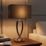 آباژور رومیزی استیل نقره ای مدل نیوا روشن روی میز چوبی