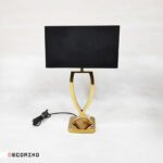 آباژور رومیزی طلایی مدل نیوا در دکوراسیون اتاق نشیمن کنار مبل