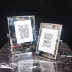 دو قاب عکس شیشه‌ای و فلزی نقره‌ای با پایه، مناسب دکوراسیون لوکس.