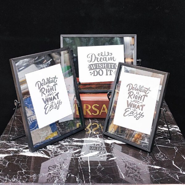 دکوراسیون سه گانه قاب عکس فلزی ساده روی میز مشکی و سفید.