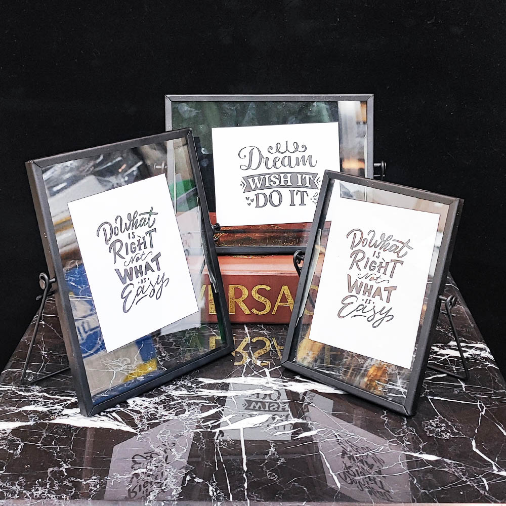 دکوراسیون سه گانه قاب عکس فلزی ساده روی میز مشکی و سفید.