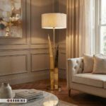 عکس ژورنالی آباژور ایستاده لوکس طلایی با نورپردازی گرم در کنار مبلمان راحتی