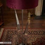 نمای نزدیک پایه فلزی آباژور طرح لاله رنگ نقره ای و شید زرشکی روی فرش