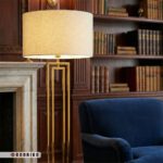 نمای نزدیک آباژور کنار سالنی طلایی مدرن با طراحی هندسی مستطیل و کلاهک پارچه ای روشن