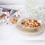 پیاله سرامیکی طرح ماربل پر از آجیل که روی پیش دستی ست خود قرار گرفته است