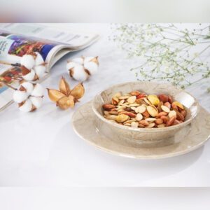 پیاله سرامیکی طرح ماربل پر از آجیل که روی پیش دستی ست خود قرار گرفته است