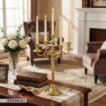 شمعدان ۵ شعله فلزی طلایی مدل سیلوین با شمع‌های روشن روی رانر میز