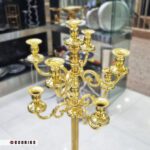 جزئیات طراحی و شاخه‌های شمعدان کنار سالنی طلایی رنگ ثابت