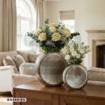 چیدمان گلدان آلومینیومی مدرن با گل رز سفید روی میز چوبی